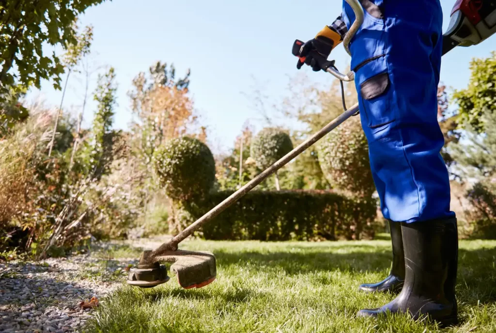 A lawn being trimmed by someone with a trimmer from RSM Property Solutions in Oxfordshire to show the garden maintenance that we offer.