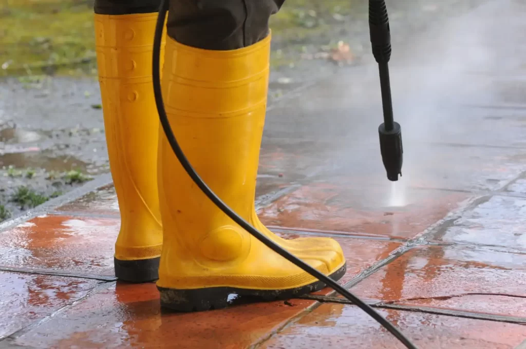 A person pressure washing some floor tiles to show the pressure washing services that RSM Property Solutions offers.