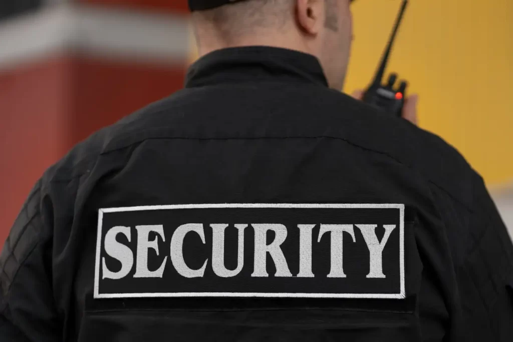 A security guard in black with the word "security" written on his back.
