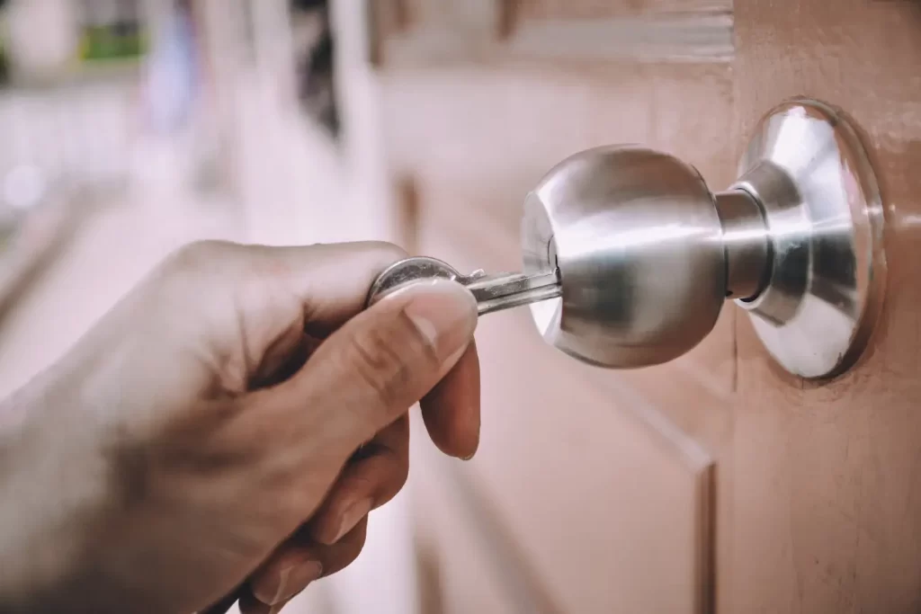 A hand with a key turning a lock in a door. This shows the locking up and unlocking that we offer as a service.